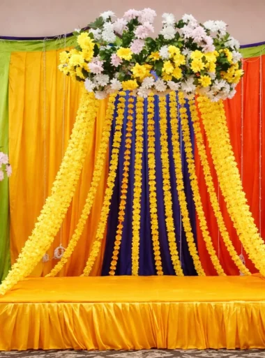 Affordable mayon stage decoration in Lahore with yellow backdrop and floral top arrangement