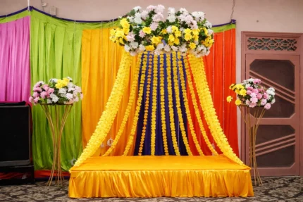 Affordable mayon stage decoration in Lahore with yellow backdrop and floral top arrangement