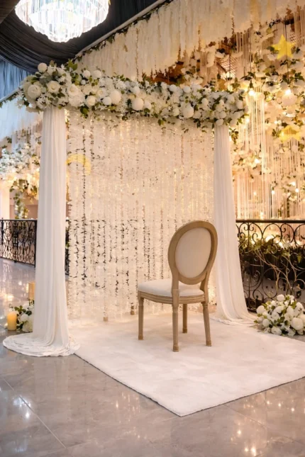 Indoor nikah stage decoration with white draped canopy, hanging floral strings and floral top border in Lahore