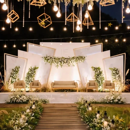 Outdoor walima stage decoration with geometric backdrop panels, warm hanging lights and floral aisle setup in Lahore