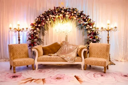 Wedding stage decoration in Lahore with floral arch backdrop, sofa seating and candle stand lights
