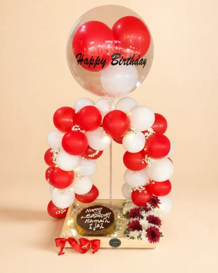 Ruby Halo birthday cake and balloon surprise with red and white flowers and Happy Birthday bubble balloon in Lahore