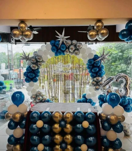 Blue white and silver birthday decoration with balloon arch, metallic star balloons, shimmer backdrop and customized age number in Lahore