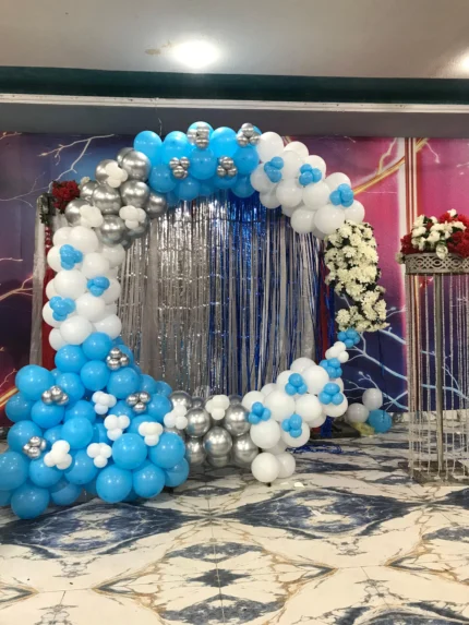 Sky blue white and silver birthday decoration with balloon arch, shimmer fringe backdrop and white floral accents in Lahore