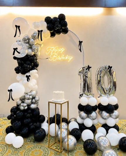 Black white and silver birthday decoration with balloon arch, bow details, Happy Birthday neon sign and customized age numbers in Lahore