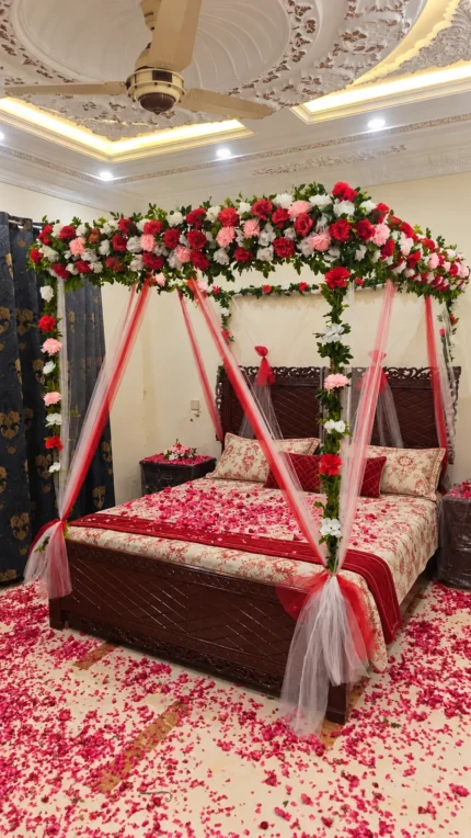 Artificial red, pink and white canopy flowers combined with fresh marjoram greenery in a Lahore bridal bedroom