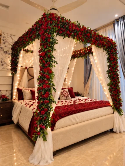 Fresh red flowers concentrated across the top of the bed canopy, with white drapes beneath in a Lahore bridal bedroom