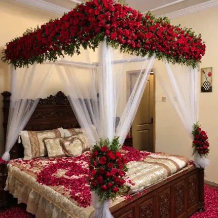 Fresh red floral coverage along the canopy top with white curtains hanging around the bed in a Lahore bridal bedroom