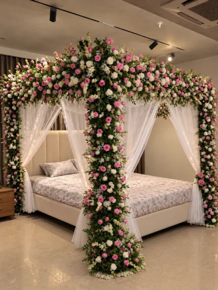 A densely arranged pink-and-white canopy made with fresh imported roses and pale fabric drapes in a Lahore bridal bedroom