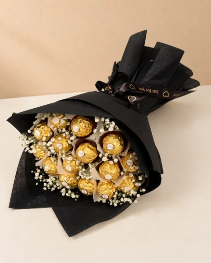 A diagonal Ferrero chocolate arrangement with white filler flowers in black wrapping.