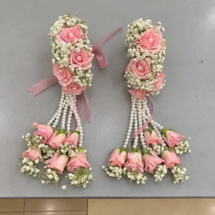Blush pink rose wrist pieces with white filler flowers, hanging pearl-style strands and clustered rose drops.