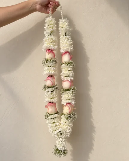 White daisy-style floral sections with blush rose bands and a white floral tassel.