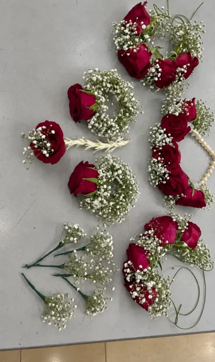Deep red rose clusters with white filler flowers and a coordinated selection of floral jewellery pieces.