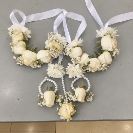 Ivory roses and white filler flowers with white ribbon ties and pearl-style earring strands.