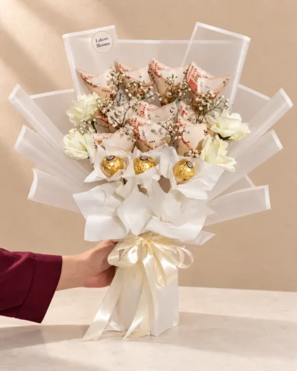 Ivory and blush roses with curled notes and gold-wrapped chocolate accents.