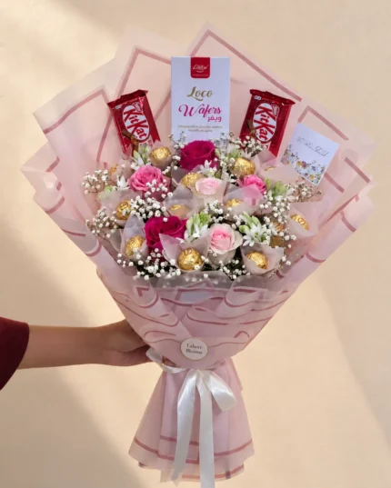 Pink and ivory flowers with chocolate bars and gold-wrapped chocolates in pink wrapping.