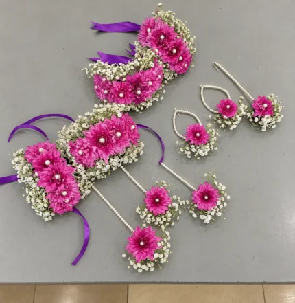 Magenta flowers with white filler flowers, pearl-style centres and purple ribbon ties.