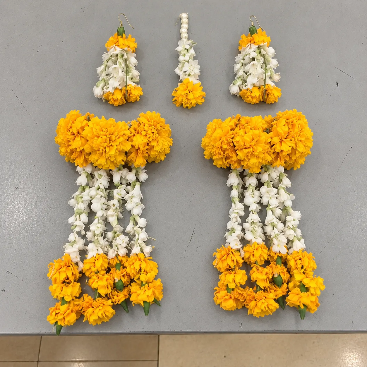 Marigold Bridal Kalire Jewellery Set Yellow-orange marigold clusters with long white floral strands and marigold drops, matching earrings and forehead ornament.