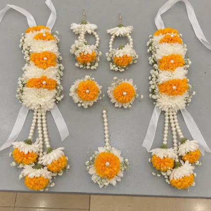 Orange marigolds and white blooms, with long floral drops, pearl-style strands and ribbon ties.