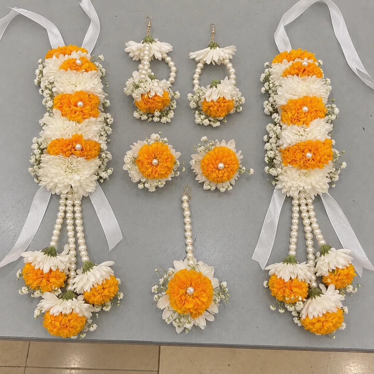 Marigold and White Bloom Bridal Jewellery Set Orange marigolds and white blooms, with long floral drops, pearl-style strands and ribbon ties.