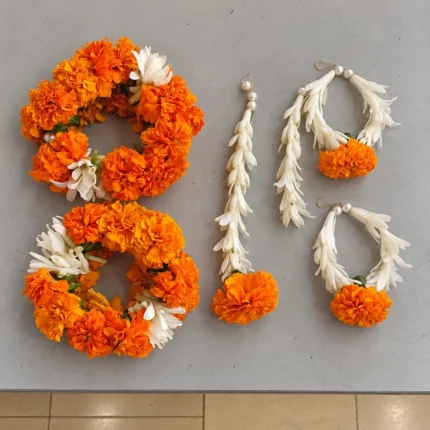 Orange marigold wrist pieces with white floral accents, earrings and forehead ornament finished with marigold drops.