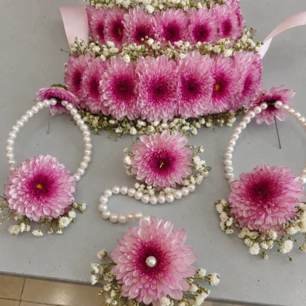 Pink chrysanthemum-style flowers bordered with white filler flowers and pearl-style strands on coordinating pieces.