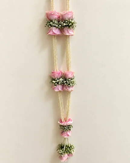 Pink rose clusters spaced along exposed pearl-style strings, with white floral accents and a lower flower drop.