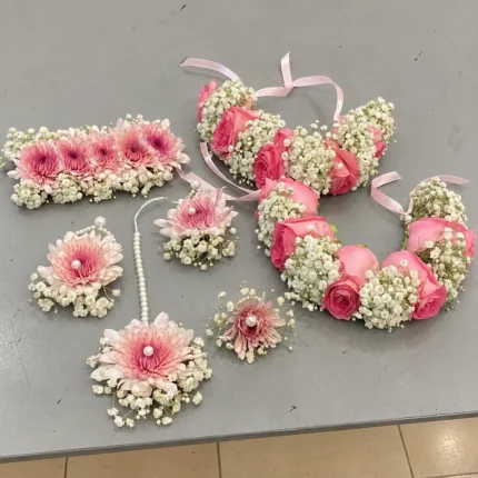 Pink roses and pink chrysanthemum-style blooms with white filler flowers, ribbon ties and matching floral ornaments.
