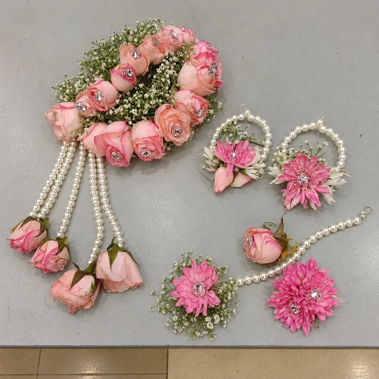 Pink Rose and Daisy Floral Jewellery Set Pink roses and pink daisy-style flowers, with white filler flowers, pearl-style strands and hanging rose drops.