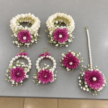 Purple flowers, white buds and small white filler flowers, matching wrist pieces, earrings and forehead ornament.