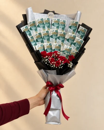 An upright banknote fan above red roses in black and silver wrapping.