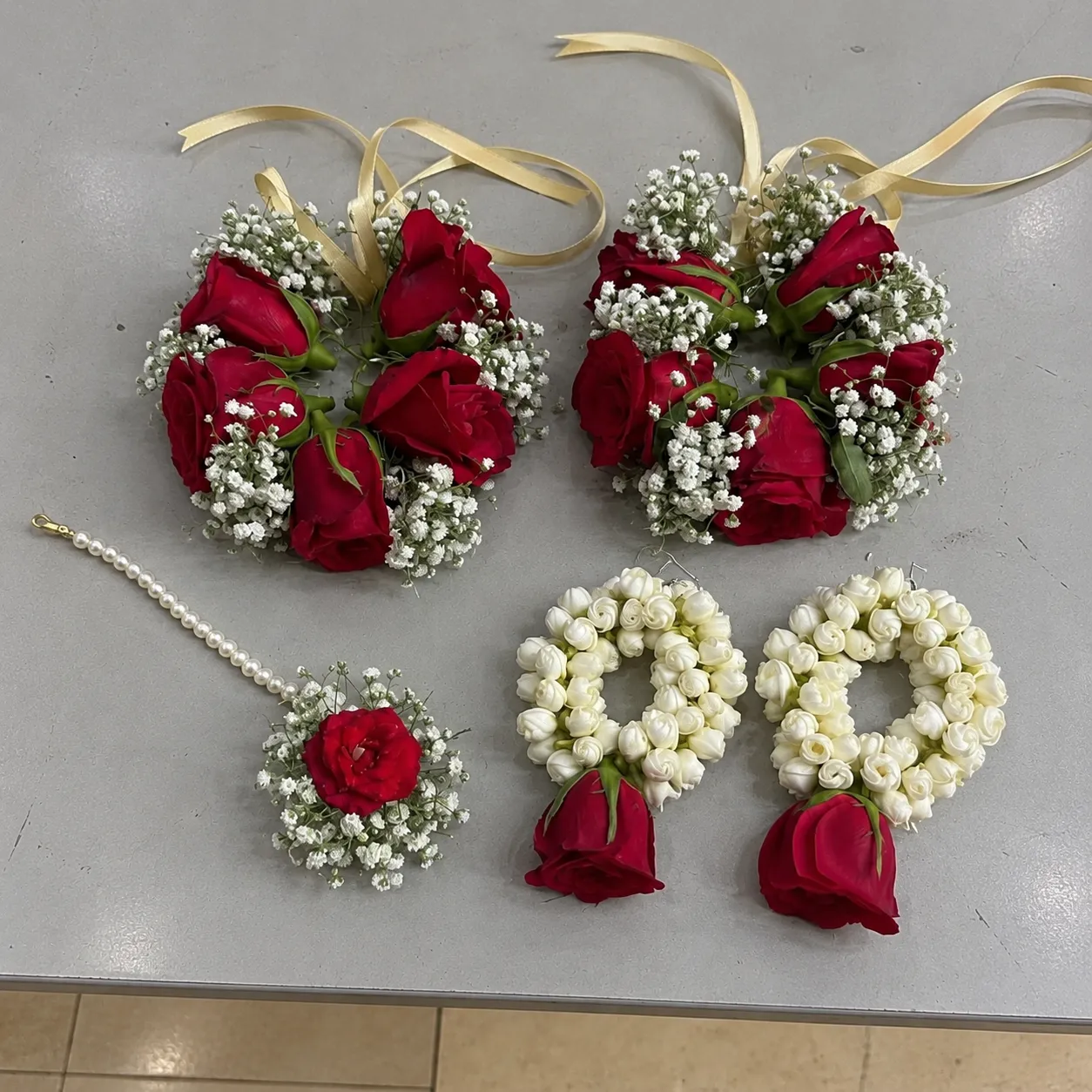 Scarlet Rose Floral Jewellery Set Red roses with white buds and filler flowers, ribbon-tied wrist pieces, matching earrings and forehead ornament.