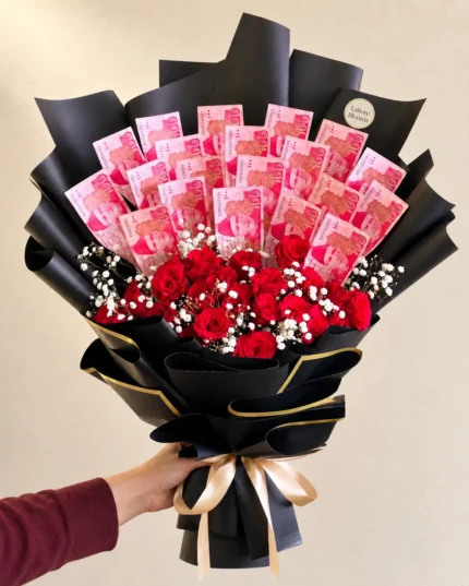 An upright banknote display above red roses in black and gold wrapping.